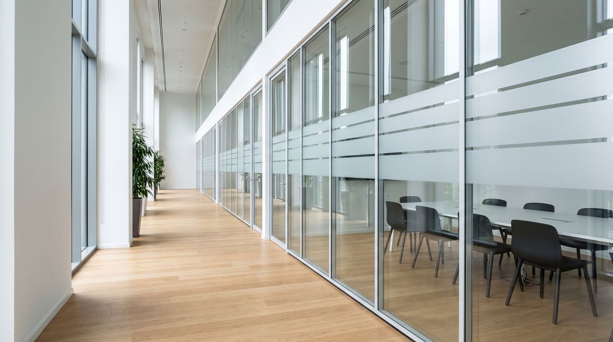 Glass-walled meeting rooms along a wide corridor